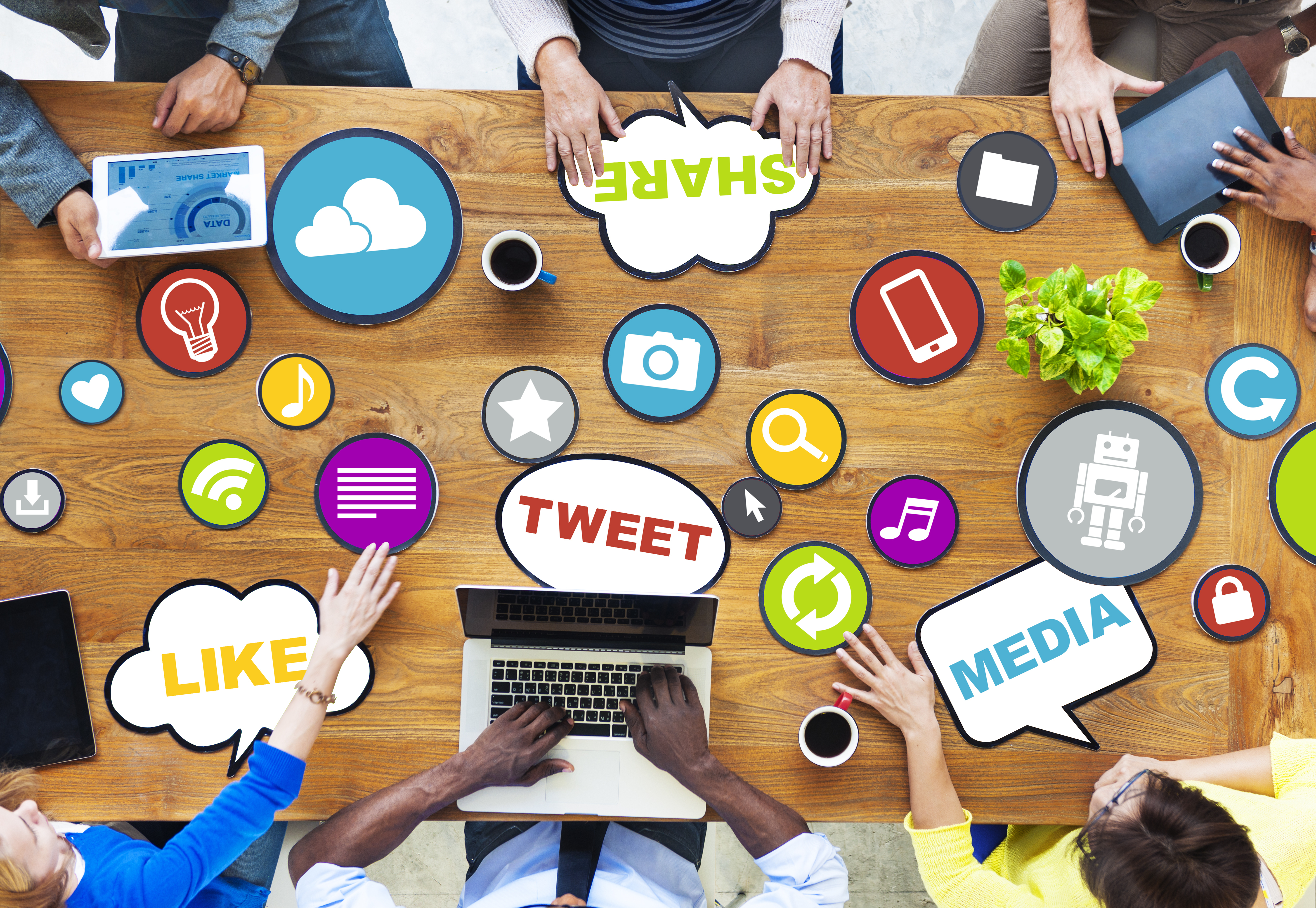 Top-down view of table with 6 people sitting around it. Speech-bubble ideas and colorful icons are laying on the table